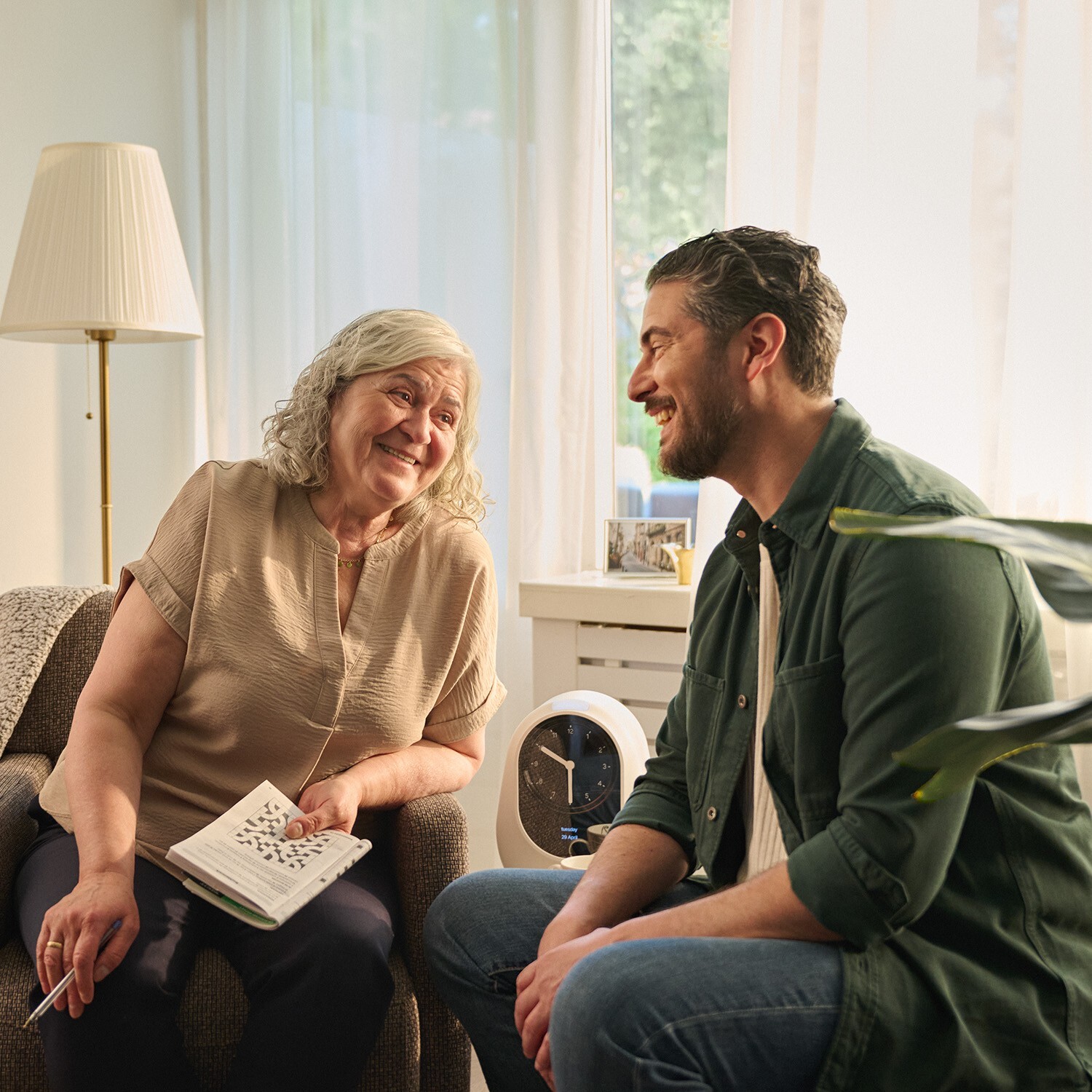 Mantelzorger in gesprek met oudere vrouw in een huiselijke setting