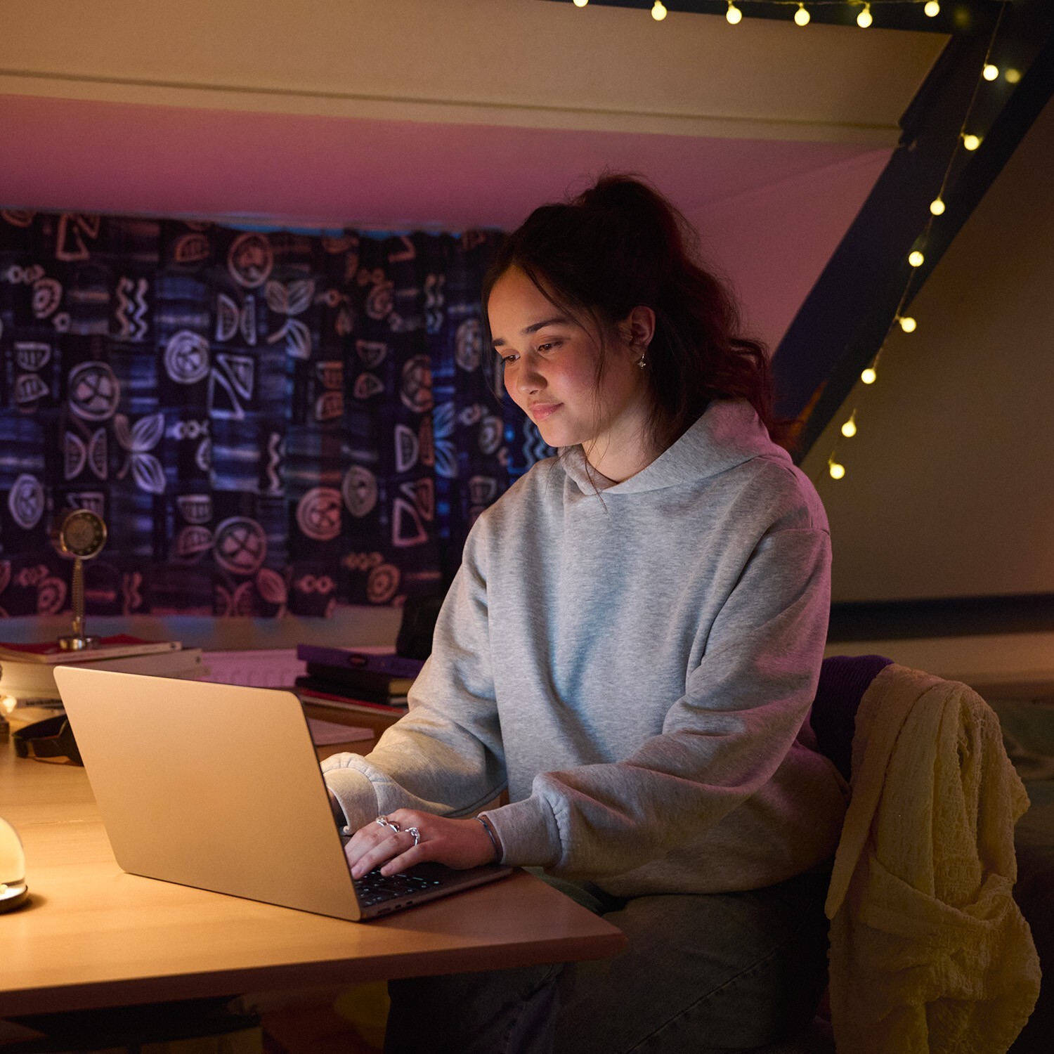 Jonge vrouw werkt 's avonds op haar laptop in haar slaapkamer